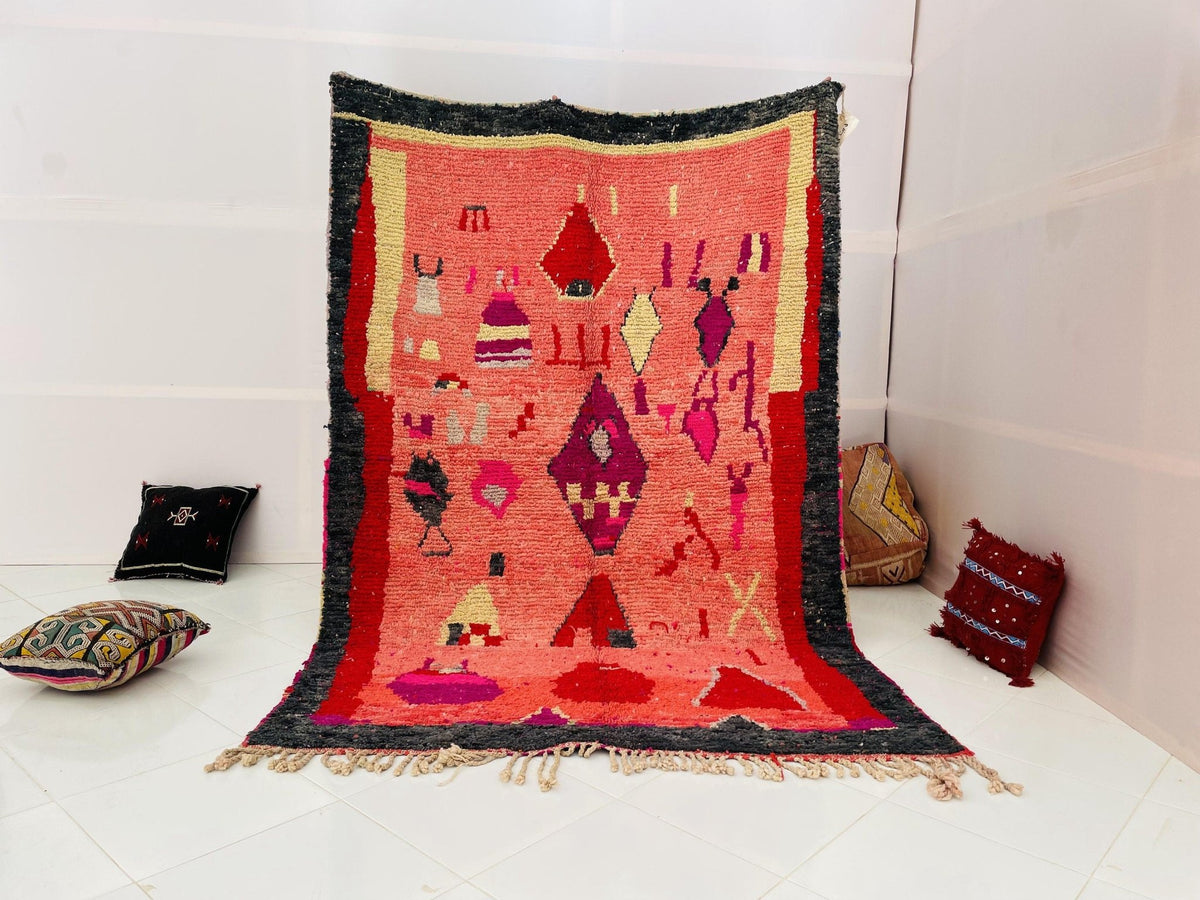 Lifestyle shot of a pink vintage Moroccan rug with colorful patterns on a white background.