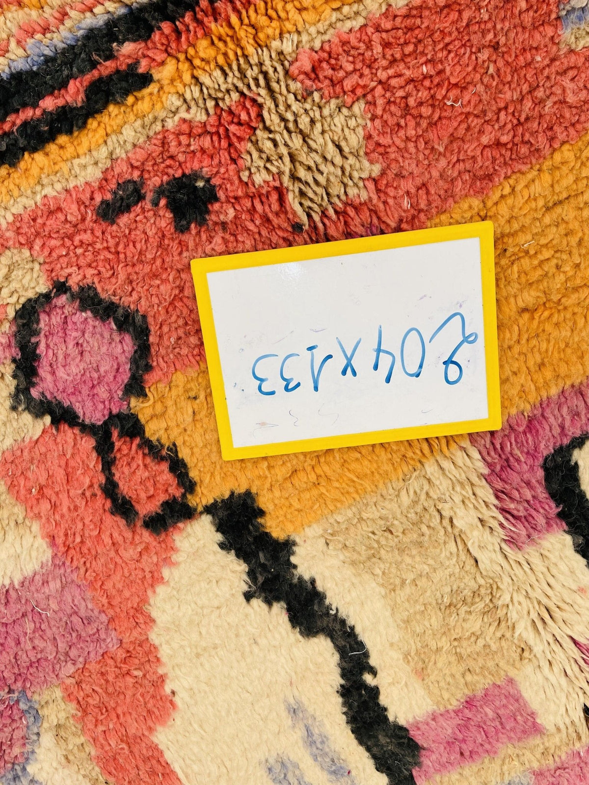 Close-up of a vintage Moroccan rug showcasing an abstract design in pink, yellow, black, and blue.