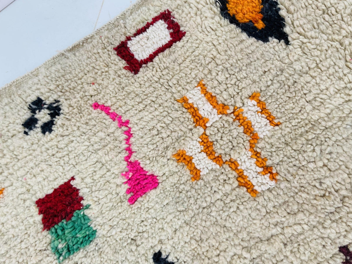 Close-up detail of a vintage Boujaad Moroccan rug featuring tribal designs in red, orange, and white.