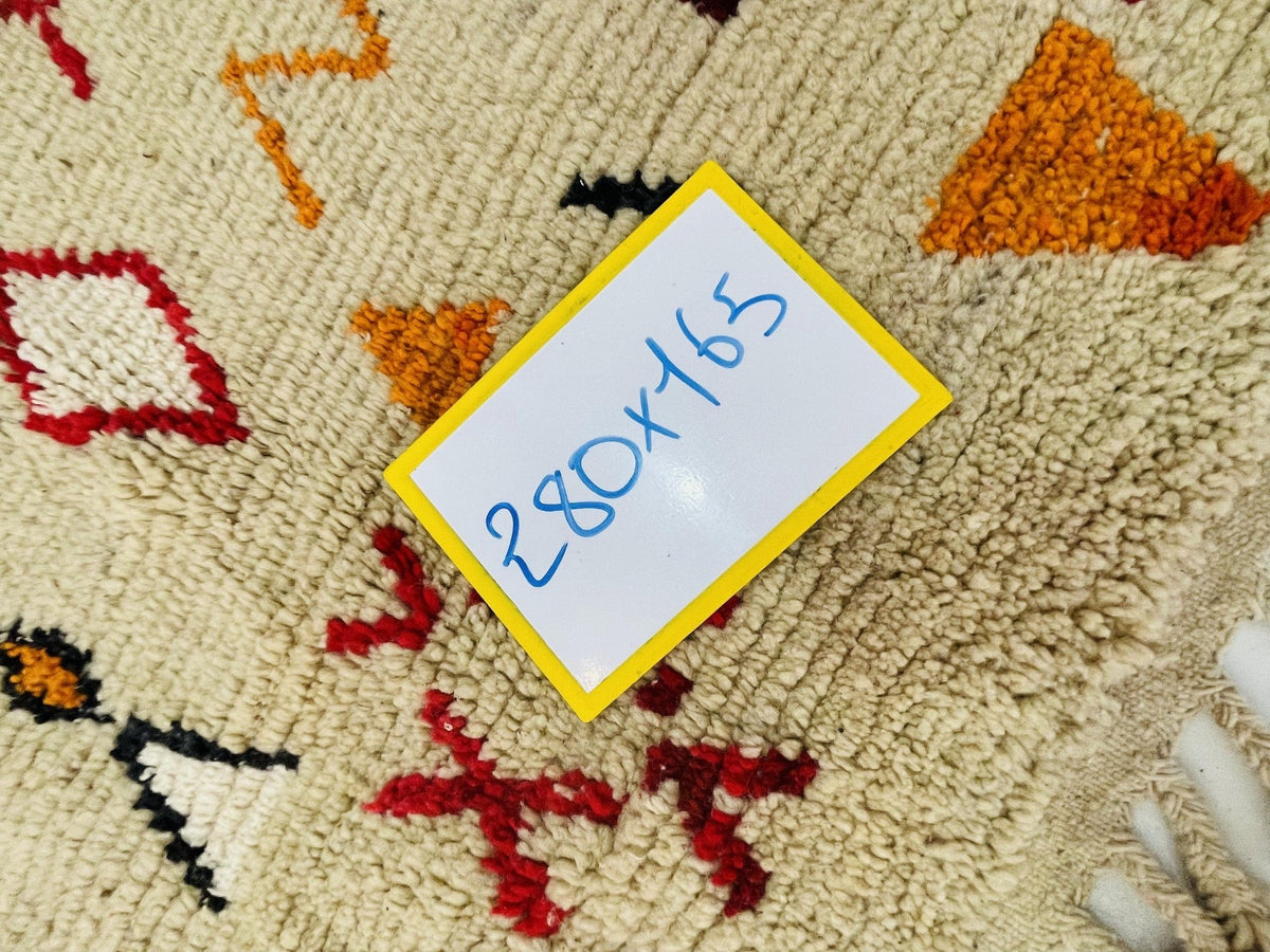 Detail view of a vintage Boujaad Moroccan rug with tribal patterns in beige, red, orange, and black.