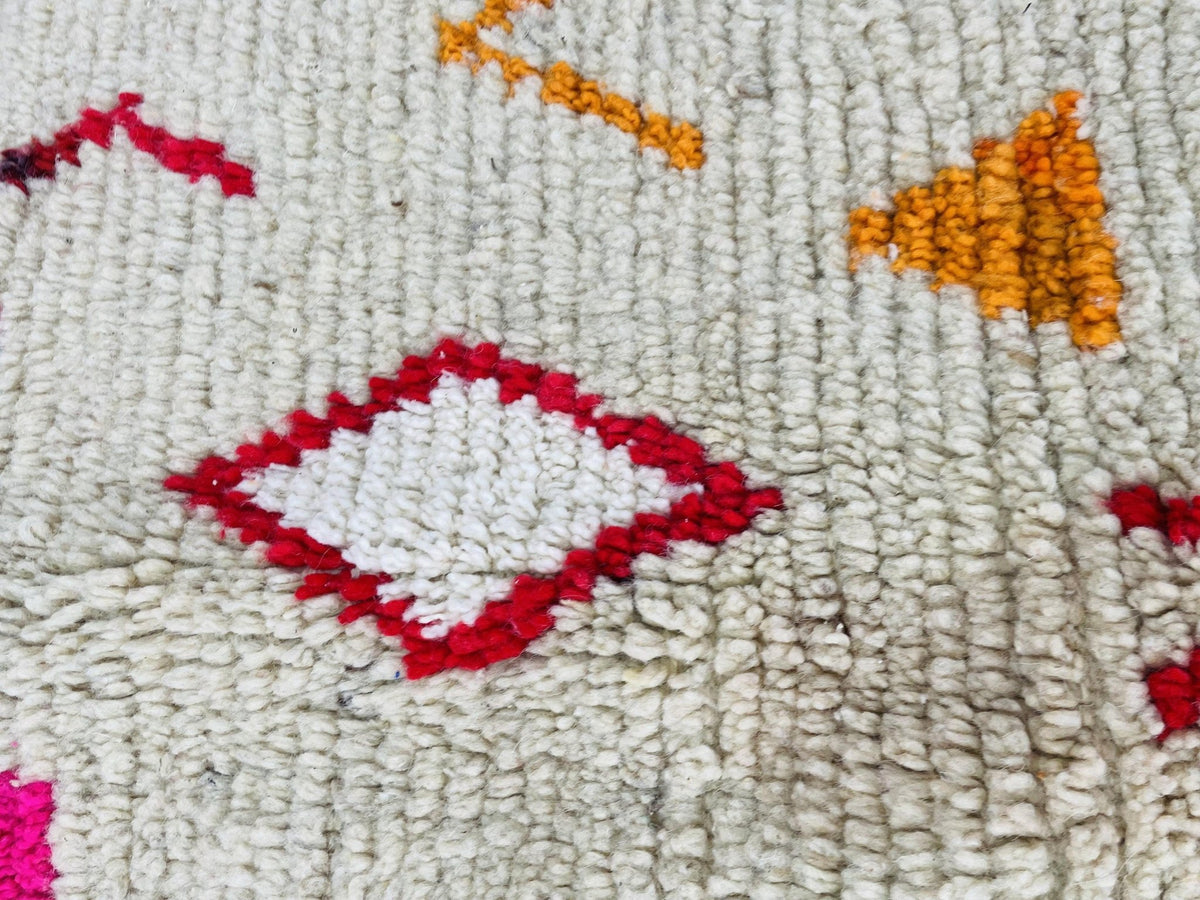 Detail shot of a vintage Boujaad Moroccan rug featuring tribal patterns in red, orange, and white.