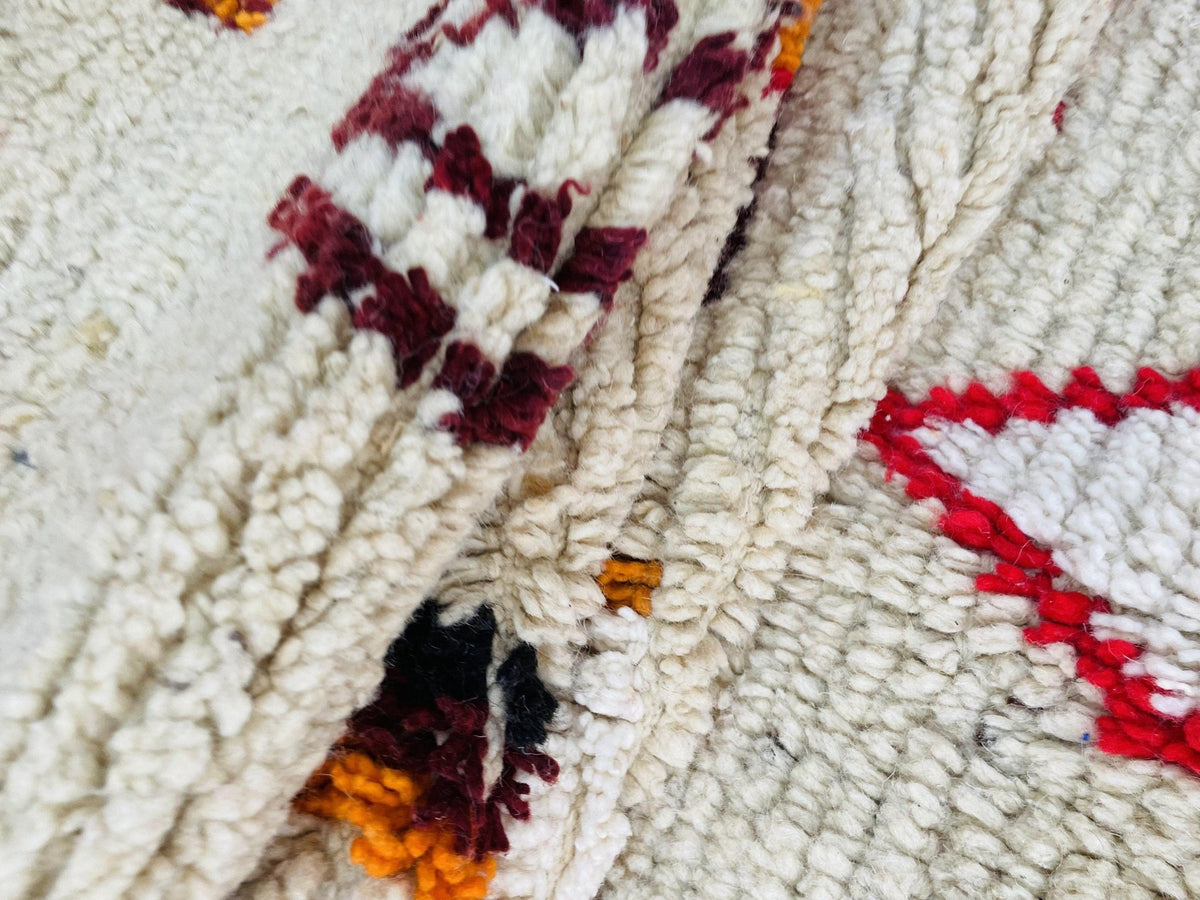 Lifestyle view of a vintage Boujaad Moroccan rug showcasing tribal designs in beige, red, and orange.