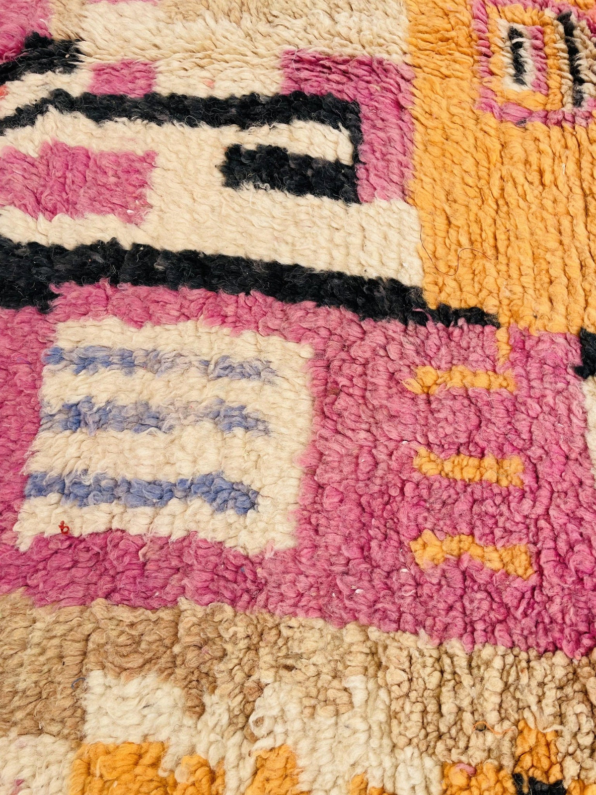 Detail shot of a vintage Moroccan rug with colorful patterns and a label present in red and beige.