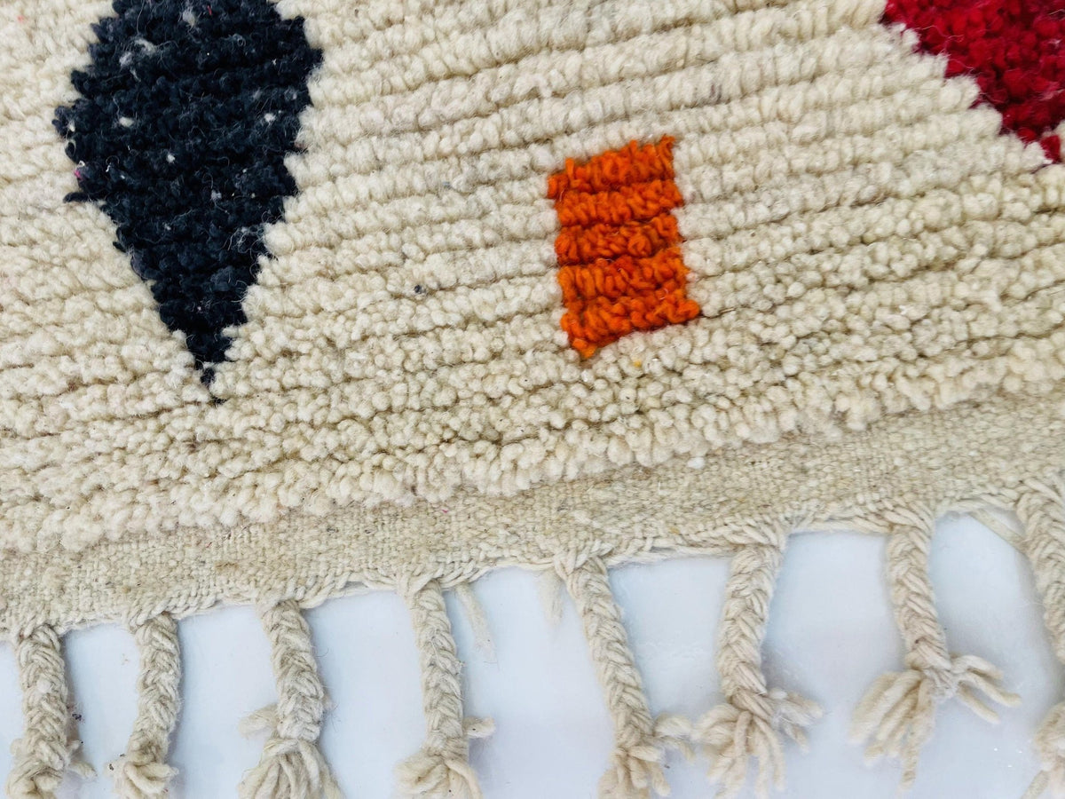 Close-up of the edge of a vintage Boujaad Moroccan rug highlighting fringe detail and vibrant colors.
