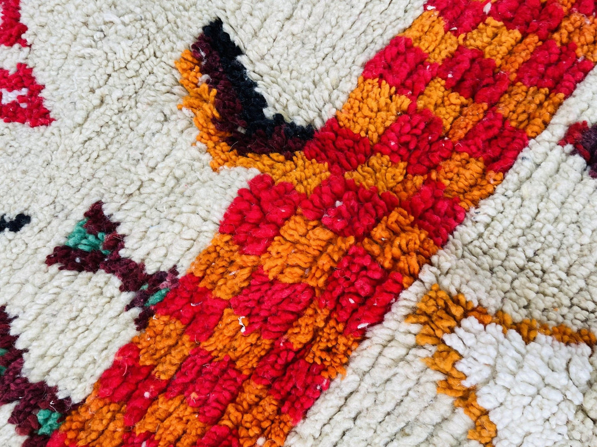 Close-up view of a vintage Boujaad Moroccan rug displaying tribal patterns in red, orange, and white.