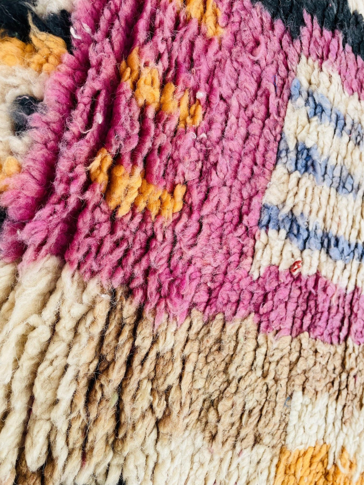 Detail close-up of a vintage Moroccan rug highlighting fringe edges and tribal patterns.