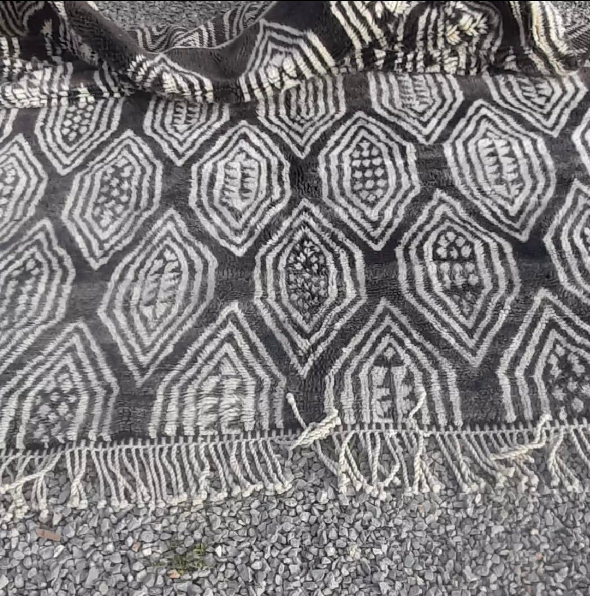 Close-up detail of the textured surface of the gray checkered Moroccan rug with intricate patterns.