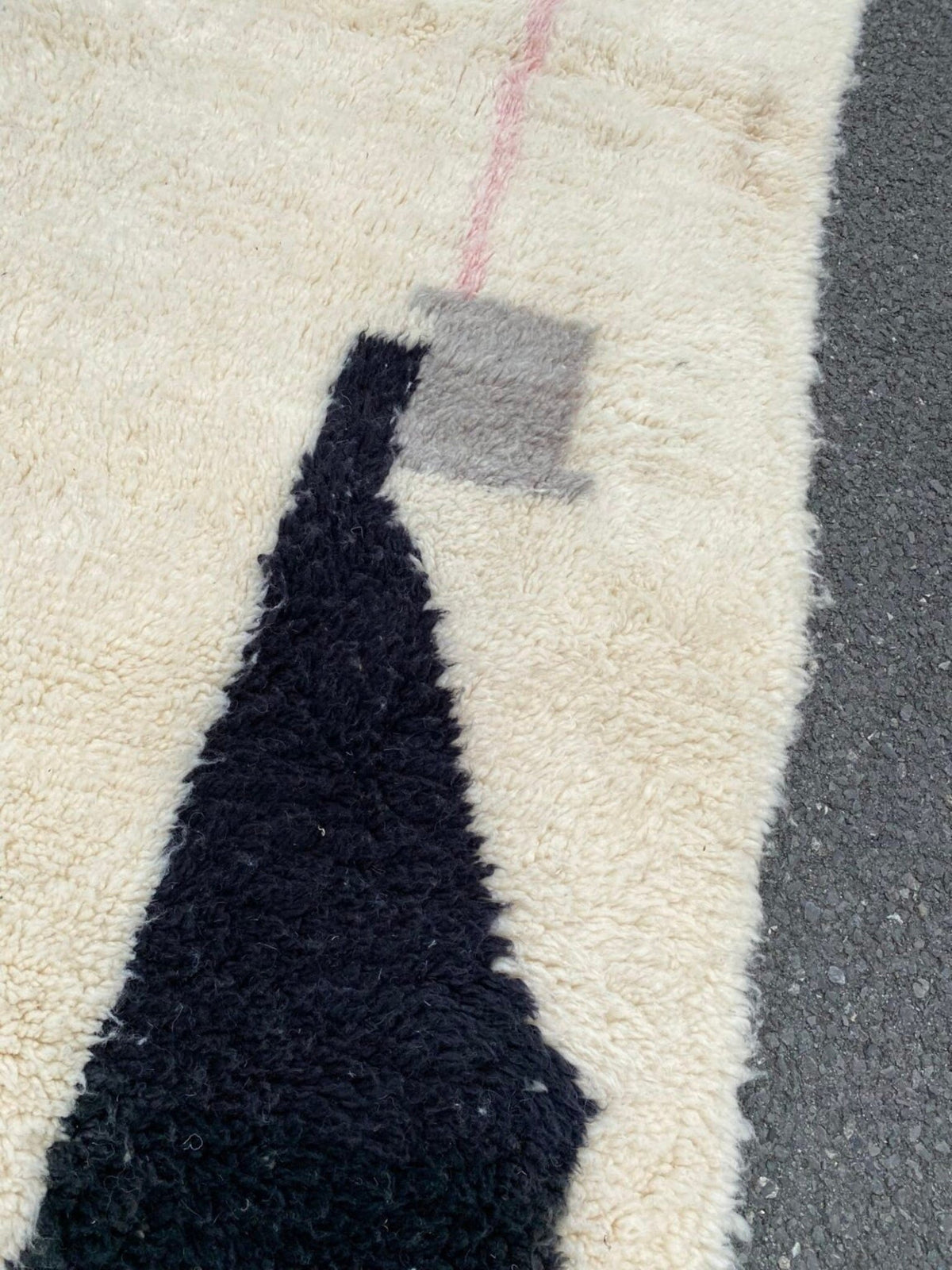 Detail close-up of the abstract design rug highlighting geometric patterns with fringe edges in black, orange, and white.