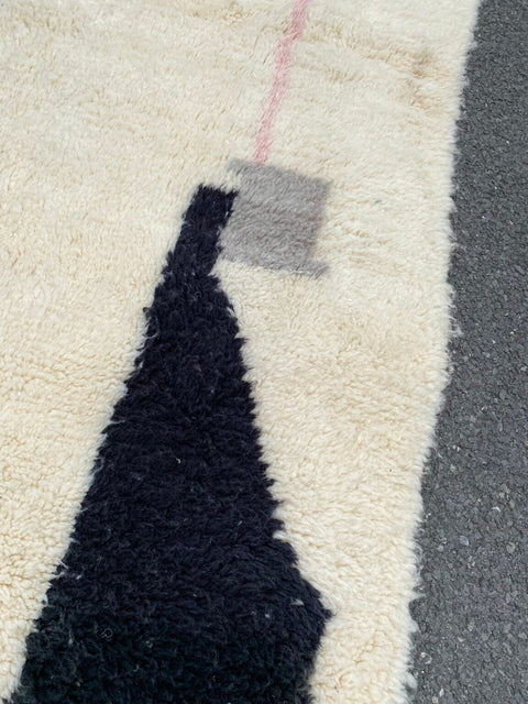 Detail close-up of the abstract design rug highlighting geometric patterns with fringe edges in black, orange, and white.