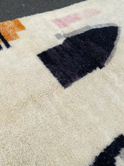 Detail close-up of the abstract design rug showcasing fringe edges and geometric patterns in black, orange, and white.