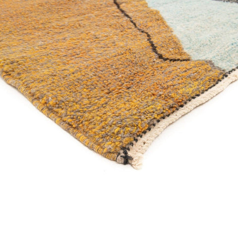 Detail close-up of the textured surface of the gray, black, and mustard abstract rug.