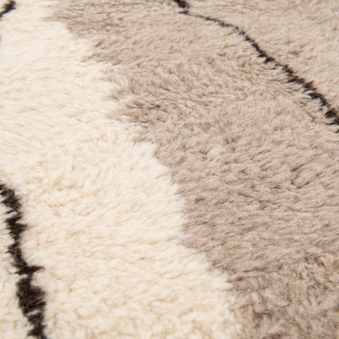 Side view of the gray, black, and mustard abstract rug highlighting its geometric design.