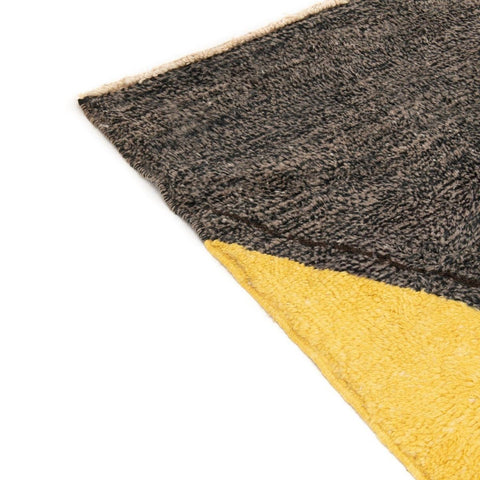 Detail close-up of the edge of the gray, black, and mustard abstract rug with a clean edge.