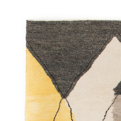 Detail close-up of the colorful accents and unique shapes on the gray, black, and mustard abstract rug.