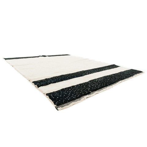 Side view of the black and cream striped Moroccan rug highlighting its textured surface.