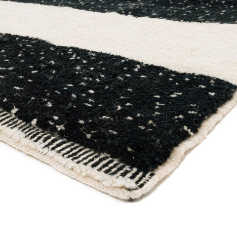 Detail view of the black and cream striped Moroccan rug showing fringe edges.