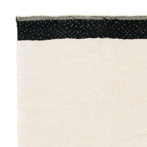 Detail close-up of the black and cream striped Moroccan rug emphasizing its soft texture.