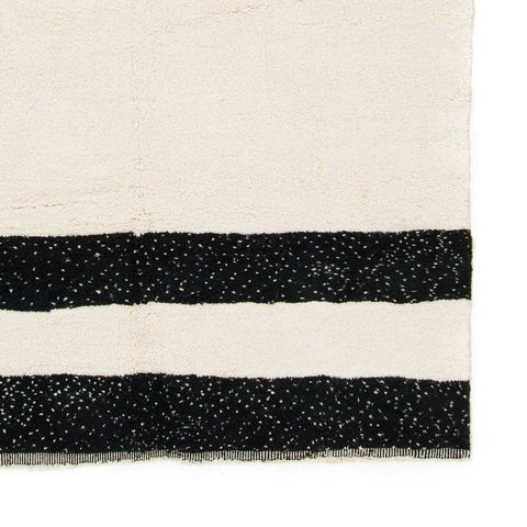 Detail close-up of the black and cream striped Moroccan rug featuring a geometric design.
