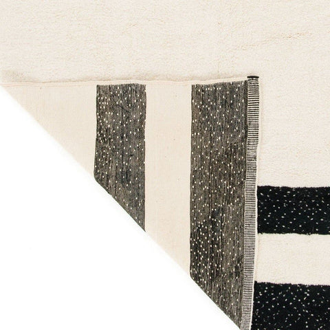 Detail close-up of the black and cream striped Moroccan rug displaying geometric patterns.