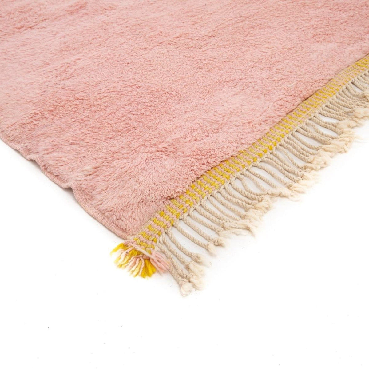 Close-up detail of the orange and pink rug featuring fringe edge and soft texture.