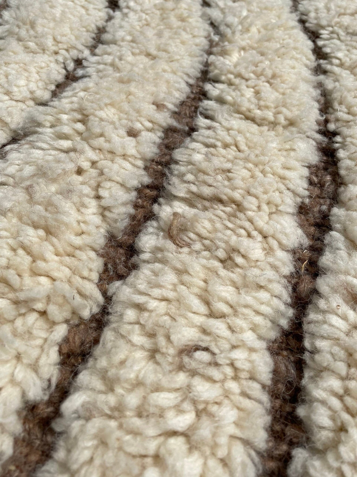 Detail close-up of the tufted brown design of the Soft Ivory Textured Custom Beni Ourain Moroccan Rug with a wavy pattern.