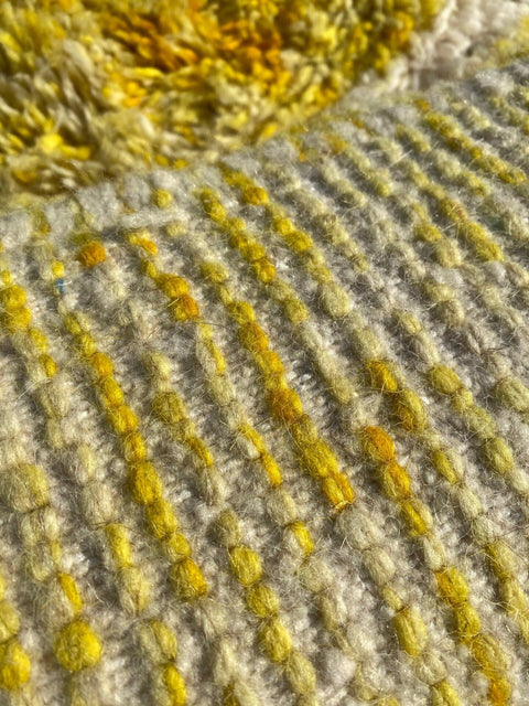 Close-up detail of a yellow Moroccan rug featuring a textured pattern and Berber design.