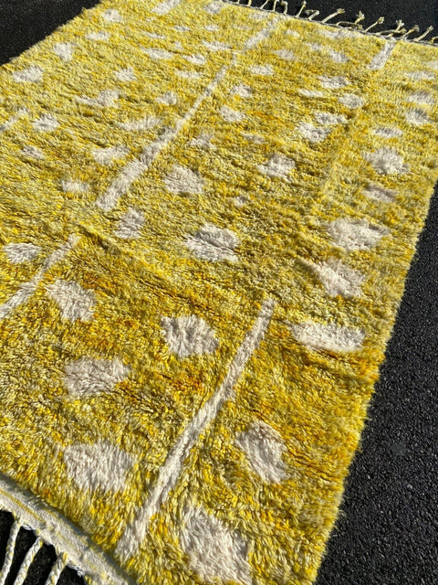 Lifestyle view of a yellow Moroccan rug showcasing fringe edges and a geometric design.