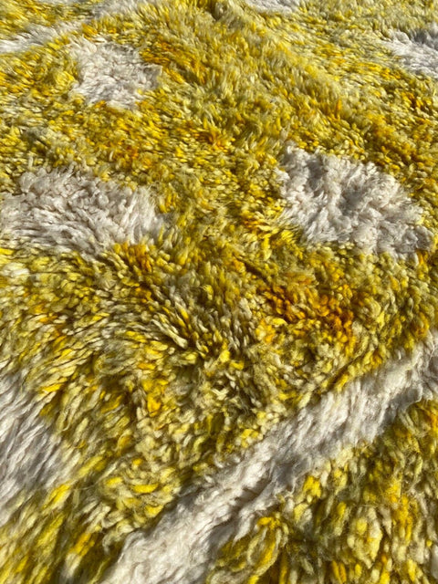 Close-up detail of a yellow Moroccan rug with a textured surface and geometric pattern.