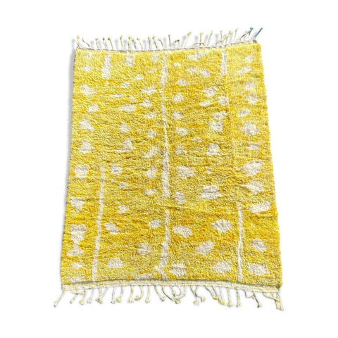 Lifestyle view of a yellow Moroccan rug featuring fringe edges and geometric patterns.