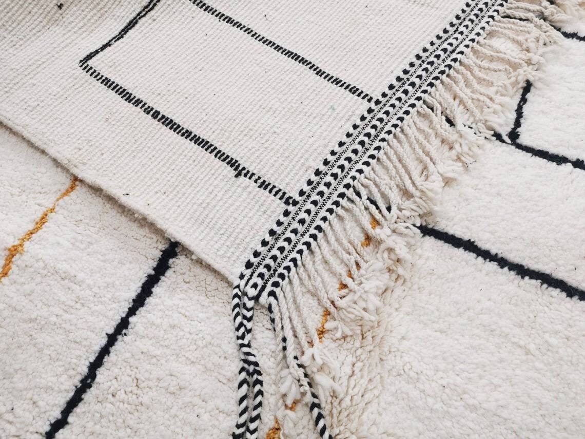 Detail shot of rug patterns displaying abstract shapes in white, black, and yellow.