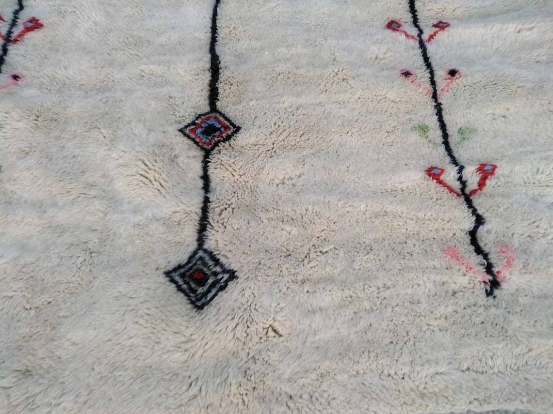 Close-up detail of a Moroccan rug with intricate patterns in white, black, and red.