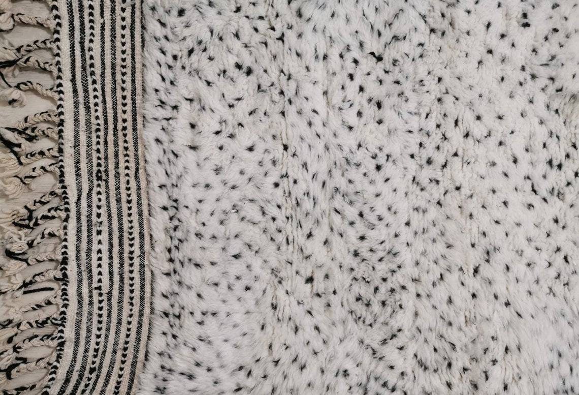 Close-up detail of a textured surface and fringe edges of the Moroccan rug.