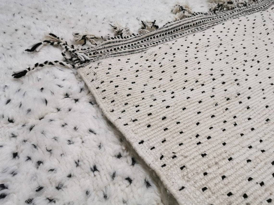 Close-up detail highlighting the textured pattern and fringe edges of the Moroccan rug.
