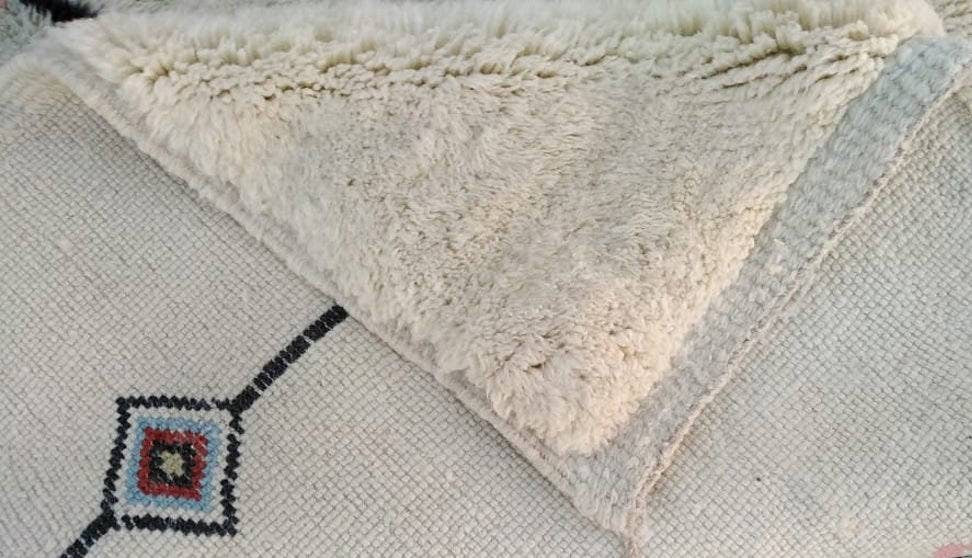 Close-up detail of a Moroccan rug showcasing fringe edges and a textured surface.