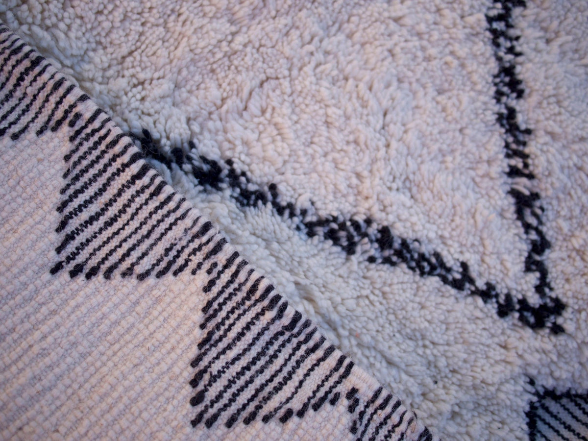 Detail close-up of the handwoven black and white geometric runner rug with textured edges.