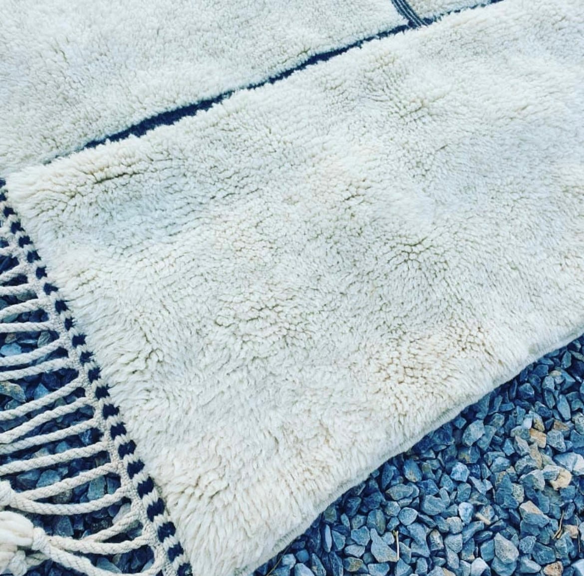 Detail close-up of a white Moroccan rug showcasing its woven texture and fringe edges.