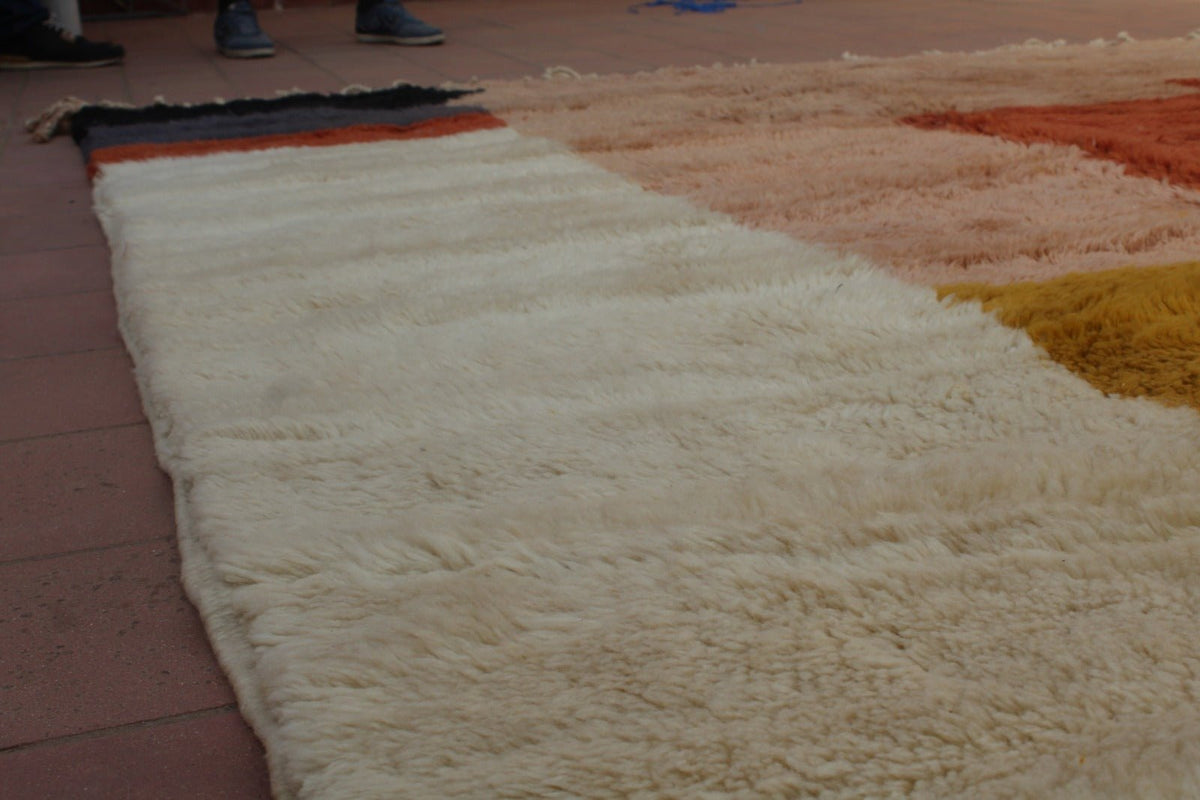 Close-up detail of a soft rug featuring a textured surface in yellow, cream, and red.