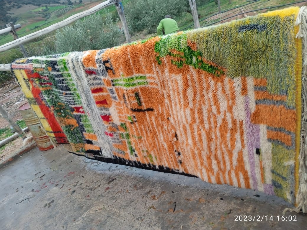 Detail shot of a colorful rug featuring orange, green, and yellow patterns.