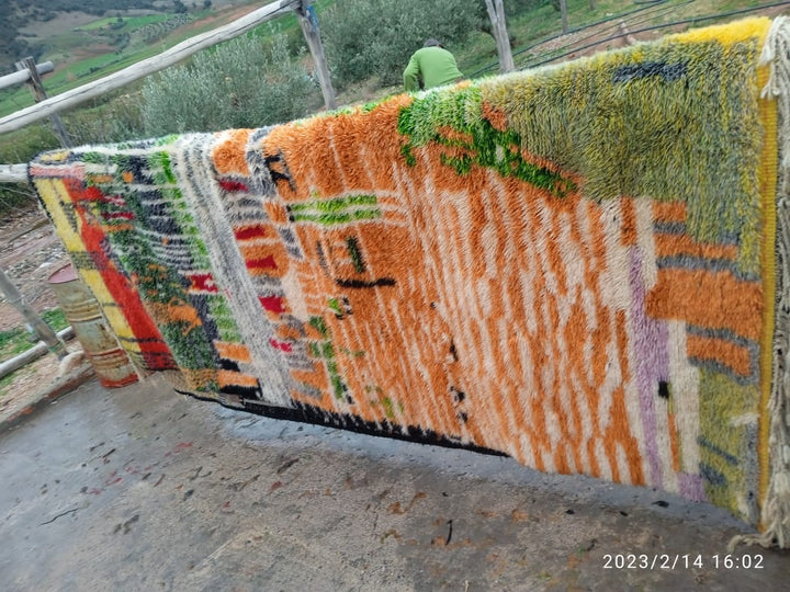 Detail shot of a colorful rug featuring orange, green, and yellow patterns.