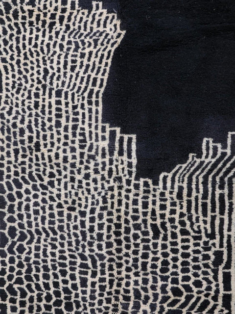 Close-up of the edge of a black rug featuring detailed stitching and pattern variation.