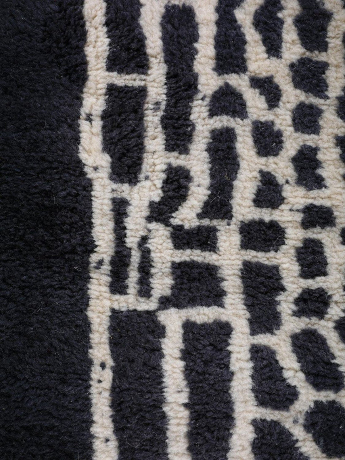 Close-up of a geometric design on a black and white rug with a soft texture.