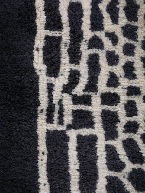 Close-up of a geometric design on a black and white rug with a soft texture.