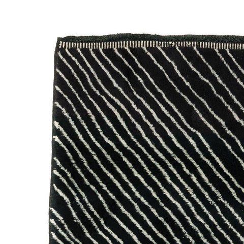 Close-up detail of a black area rug with textured lines and a soft surface.