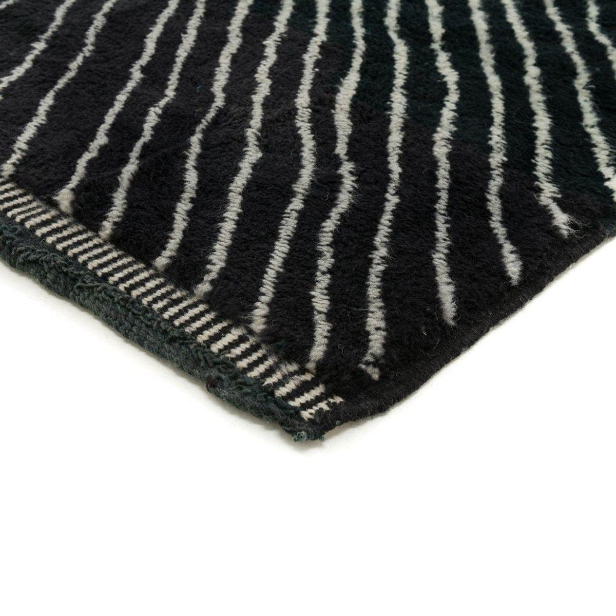 Close-up detail of a black area rug with an intricate design and woven texture.
