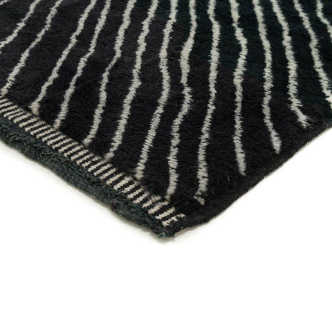 Close-up detail of a black area rug with an intricate design and woven texture.