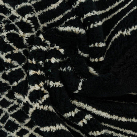 Close-up detail of a black area rug featuring an abstract pattern and thick pile.