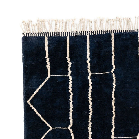 Close-up detail of a black and white abstract Beni Ourain Moroccan rug showcasing geometric lines.