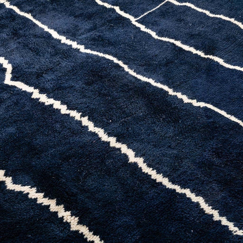 Side view of a textured black and white abstract Beni Ourain Moroccan rug with fringe edges.