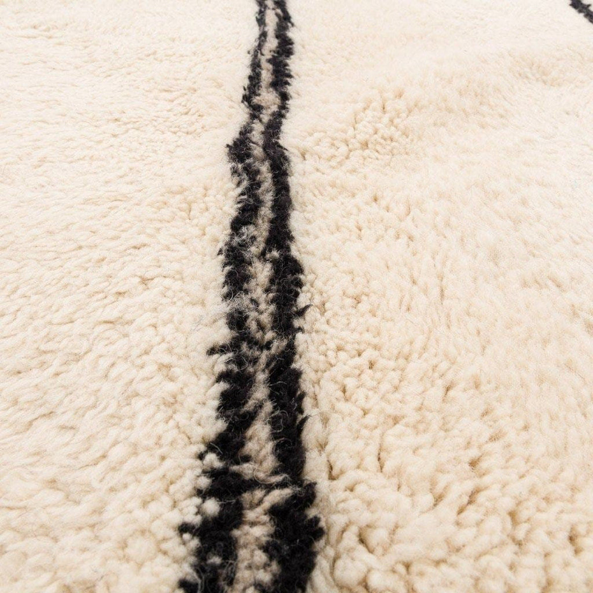 Texture detail showing soft fibers and curled edge of the beige striped Moroccan rug.