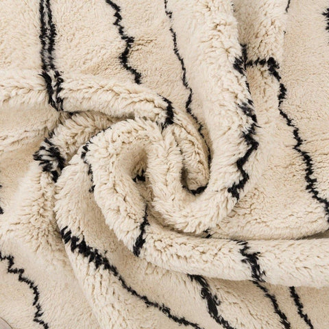 Close-up of the fringed edges and geometric design of the beige striped Moroccan rug.